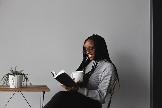 Mulher negra sentada lendo livro.