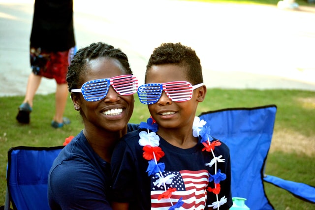 Mulher e menino negros com óculos coloridos.