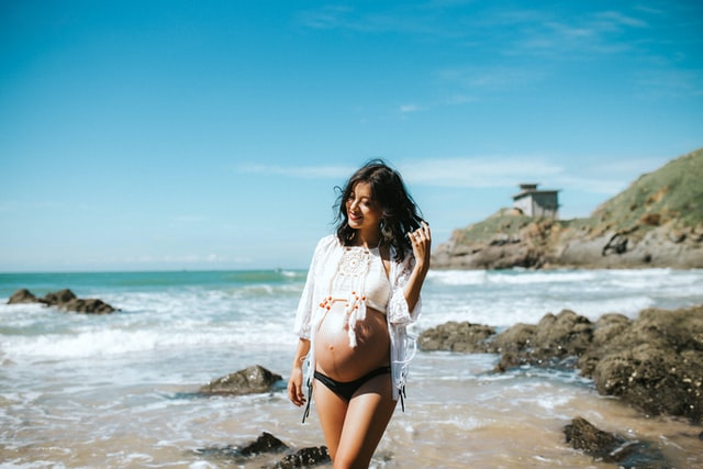 Mulher branca e grávida na praia.