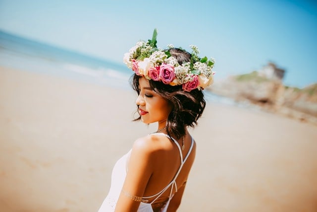 Mulher em praia com coroa de flores na cabeça