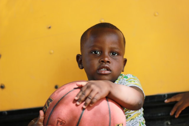Bebê negro segurando bola de basquete.