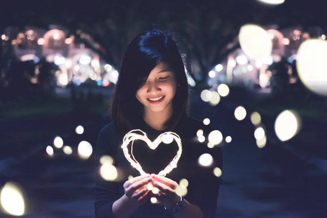 Mulher segurando luzes em formato de coração