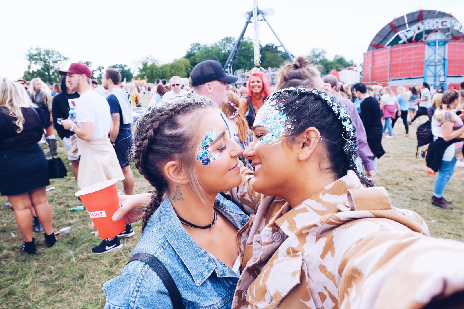 Duas mulheres brancas com os rostos próximos num festival.