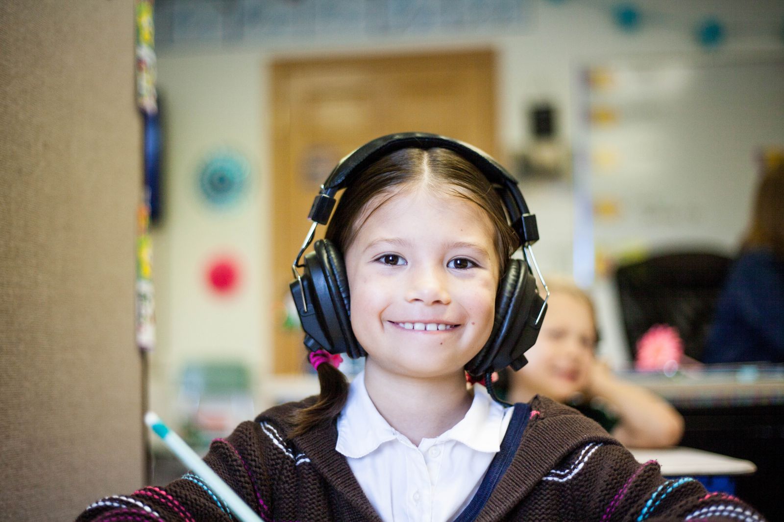 Criança com fones de ouvido na aula sorrindo