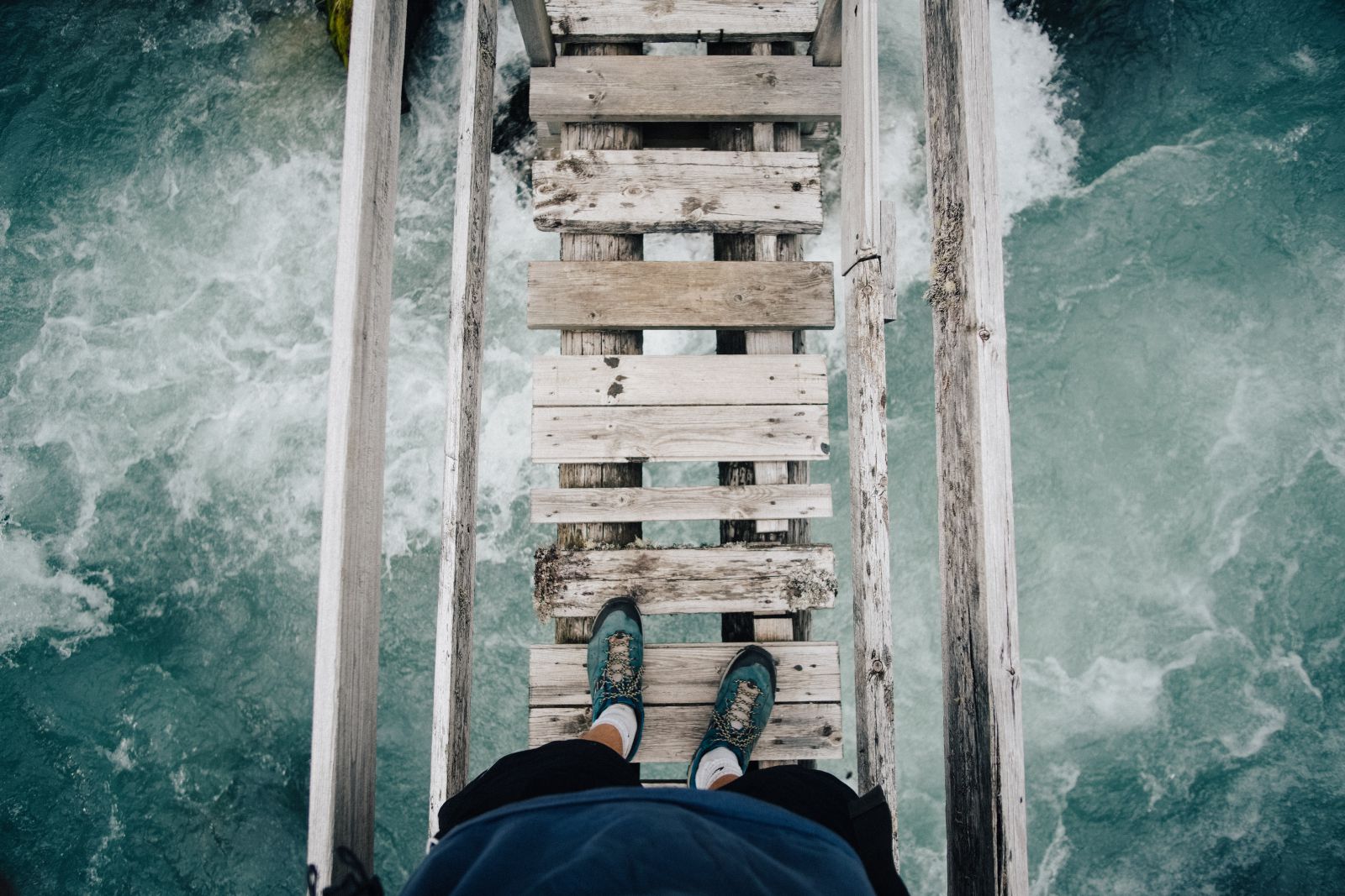 Homem em pé em uma ponte em cima do mar
