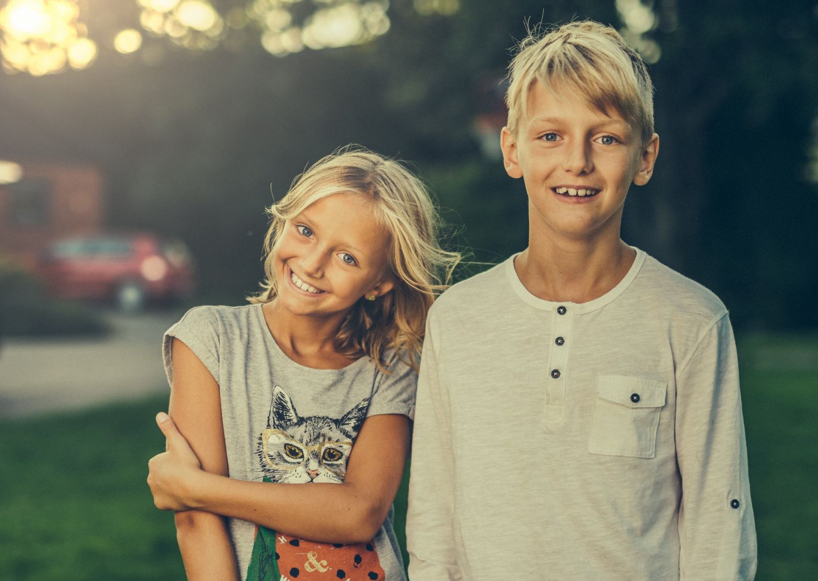 Irmã e irmão sorrindo em campo verde