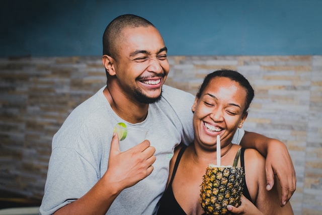 Homem e mulher negros abraçados rindo.