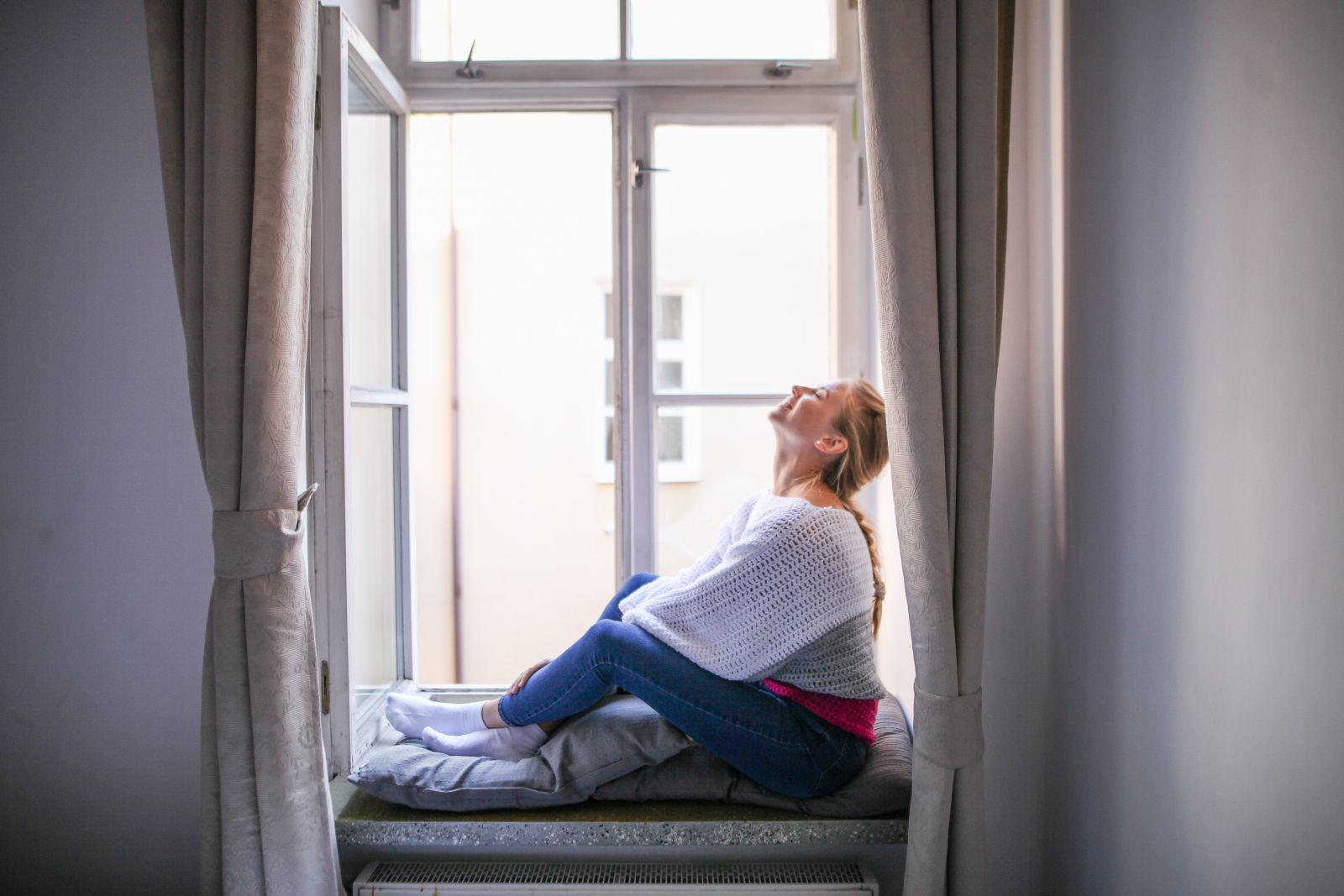 marishka Sobko/ Reshot Mulher sentada em sua janela sorrindo e olhando para cima