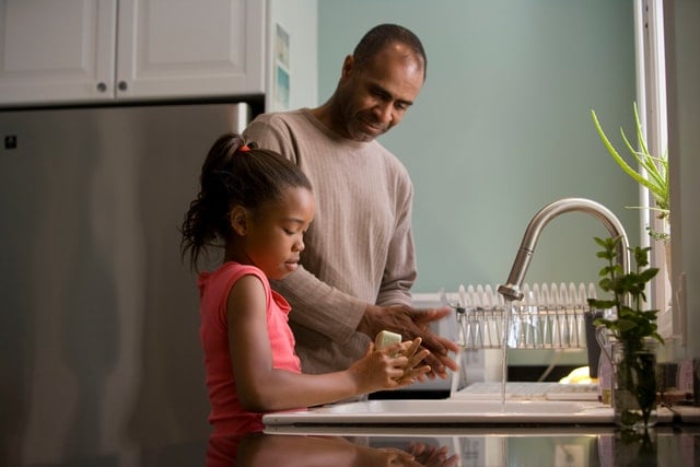 Homem e menina negros lavando louças.