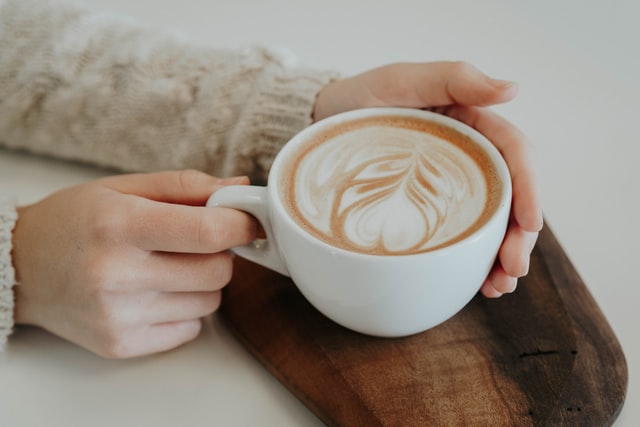 Mulher branca segurando xícara de café.
