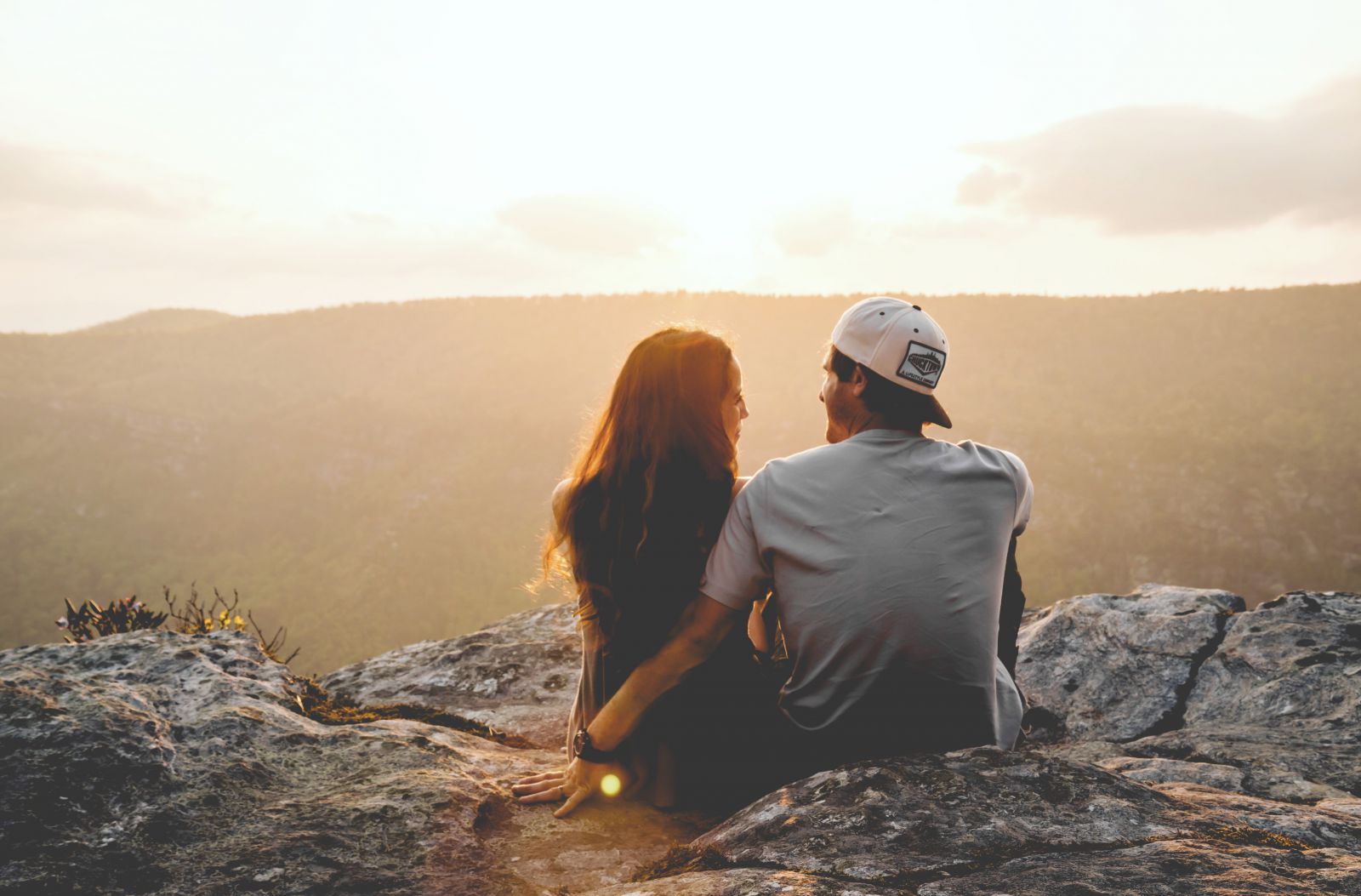 Casal sentado em uma rocha olhando para a paisagem