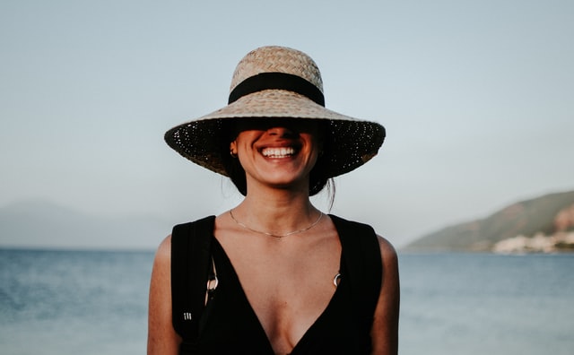 Mulher branca usando chapéu e sorrindo.