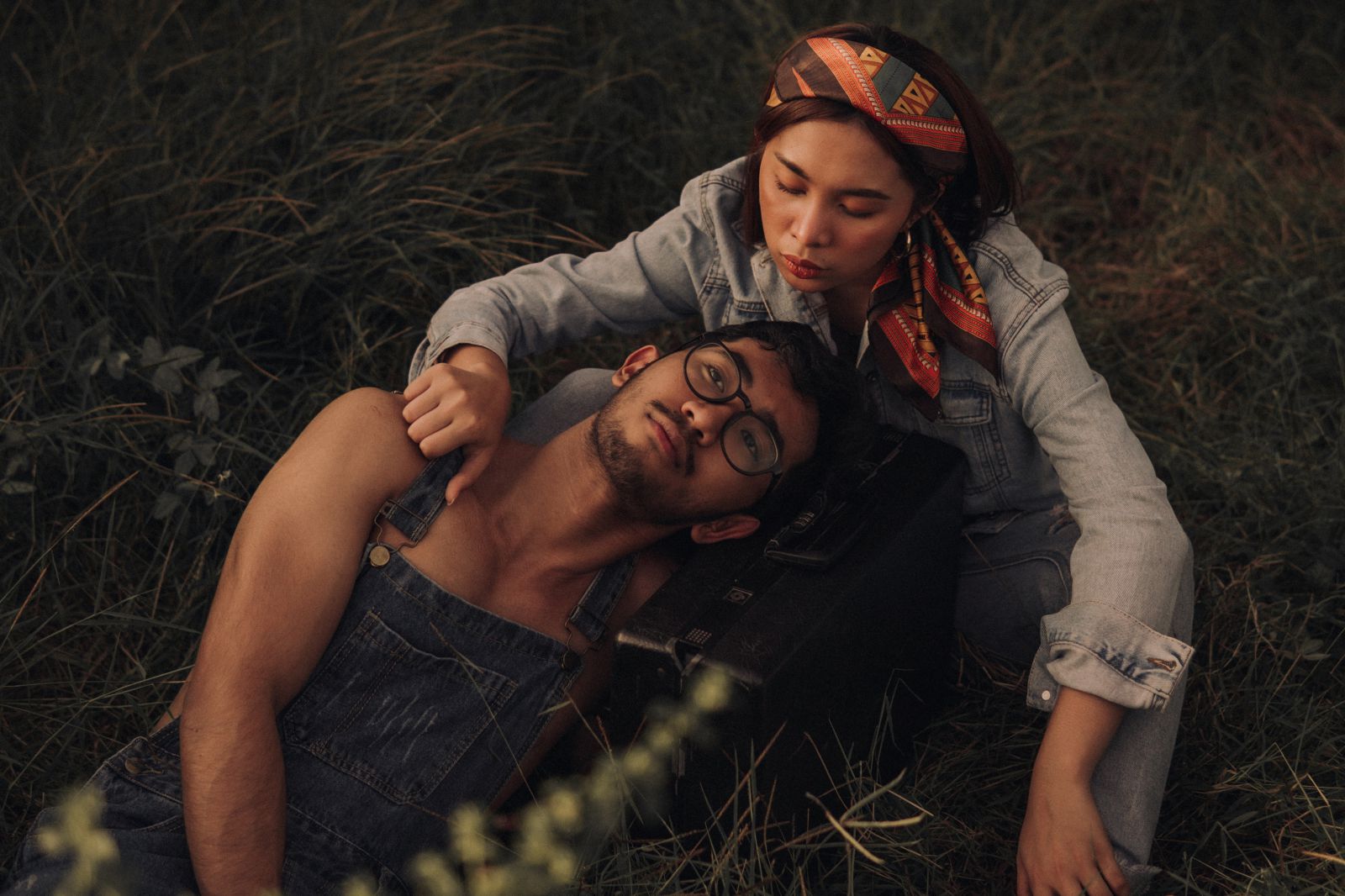 Homem e mulher deitados na grama, abraçados, olhando para cima.