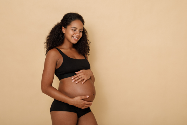 Mulher negra grávida com as mãos na barriga