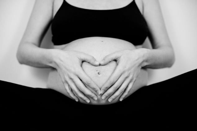 Mulher grávida fazendo símbolo de coração na barriga
