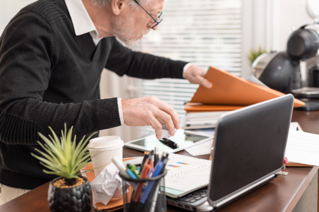 thodonal de Getty Images no Canva Homem procurando papéis em uma mesa de trabalho desorganizada