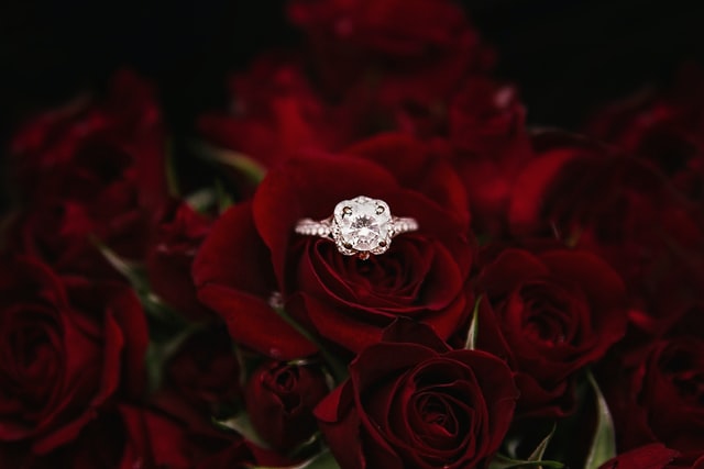 Foto de um anel de diamantes sobre um buquê de rosas