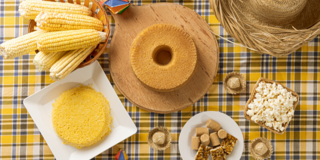 Comidas típicas de festa junina sobre uma mesa com toalha de estampa xadrez.