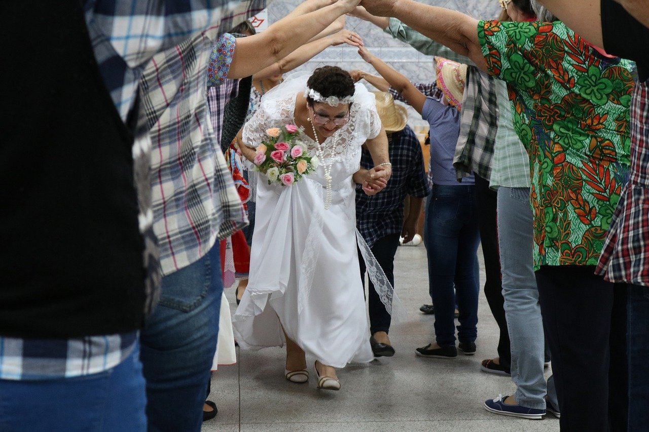 Quadrilha de festa junina, com a noiva e o noivo passando pelo túnel, feito com os braços das outras pessoas.