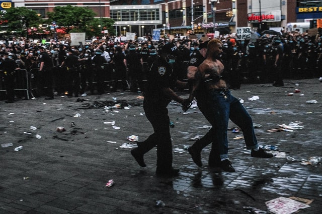 Policiais prendendo homem branco em protesto.