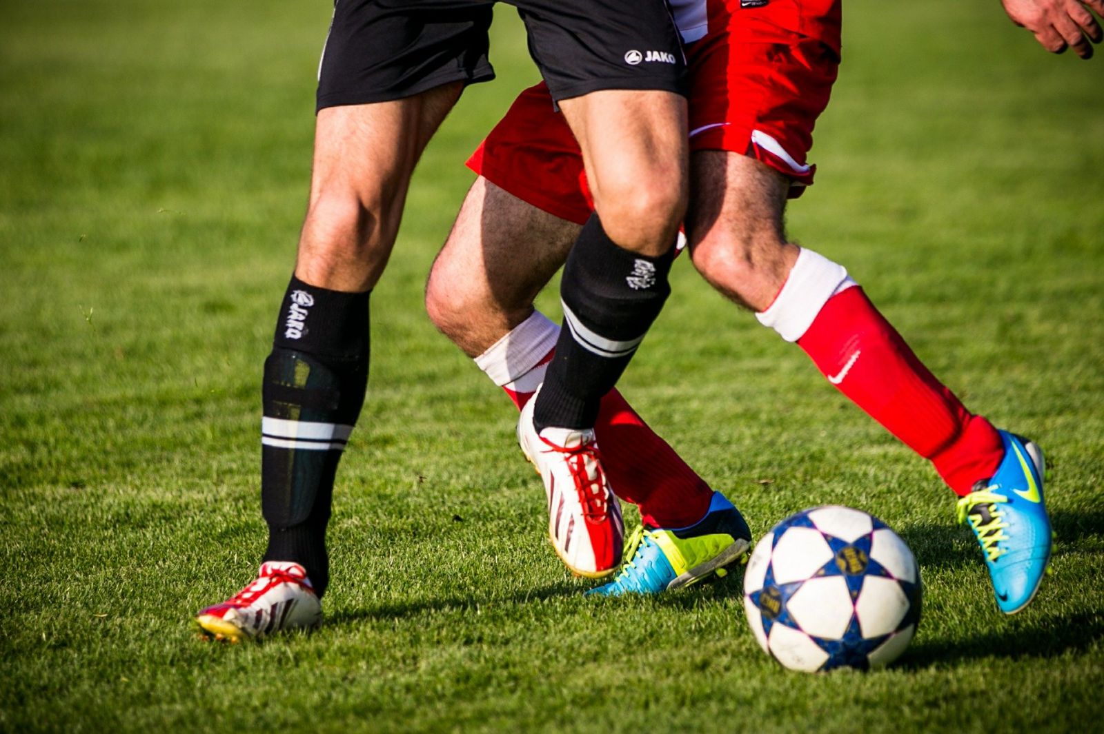 Dois pares de pernas brancas masculinas jogando futebol