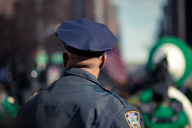 Homem negro de costas com uniforme de policial.