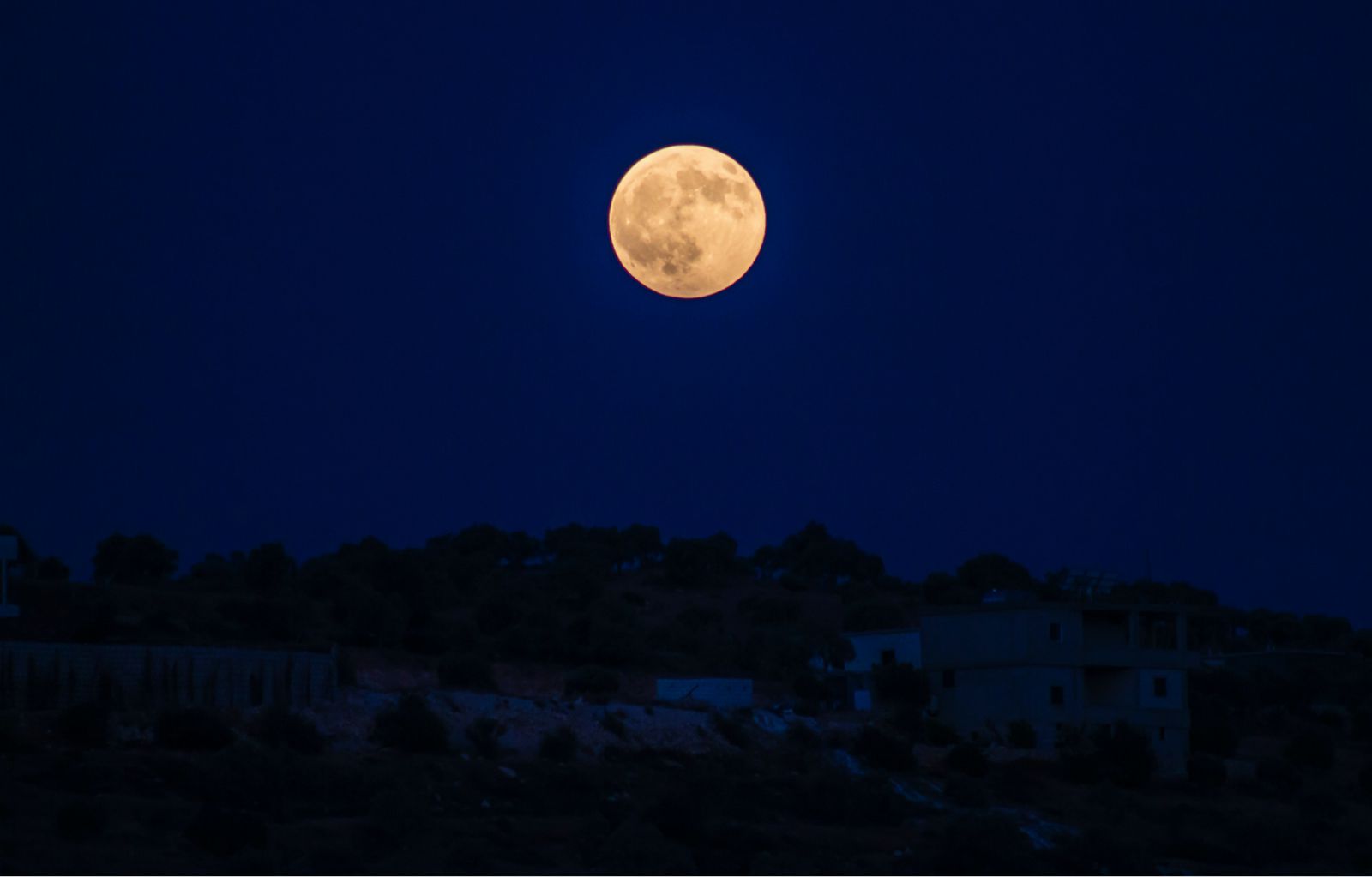 Foto da lua cheia ao anoitecer.