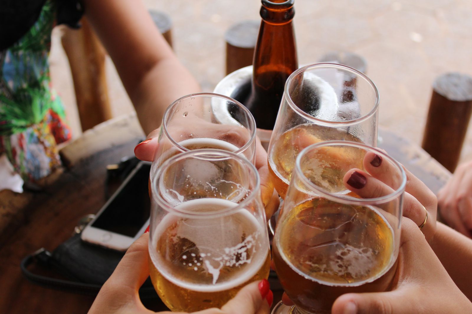 Grupo de pessoas segurando copos com cervejas e outras bebidas