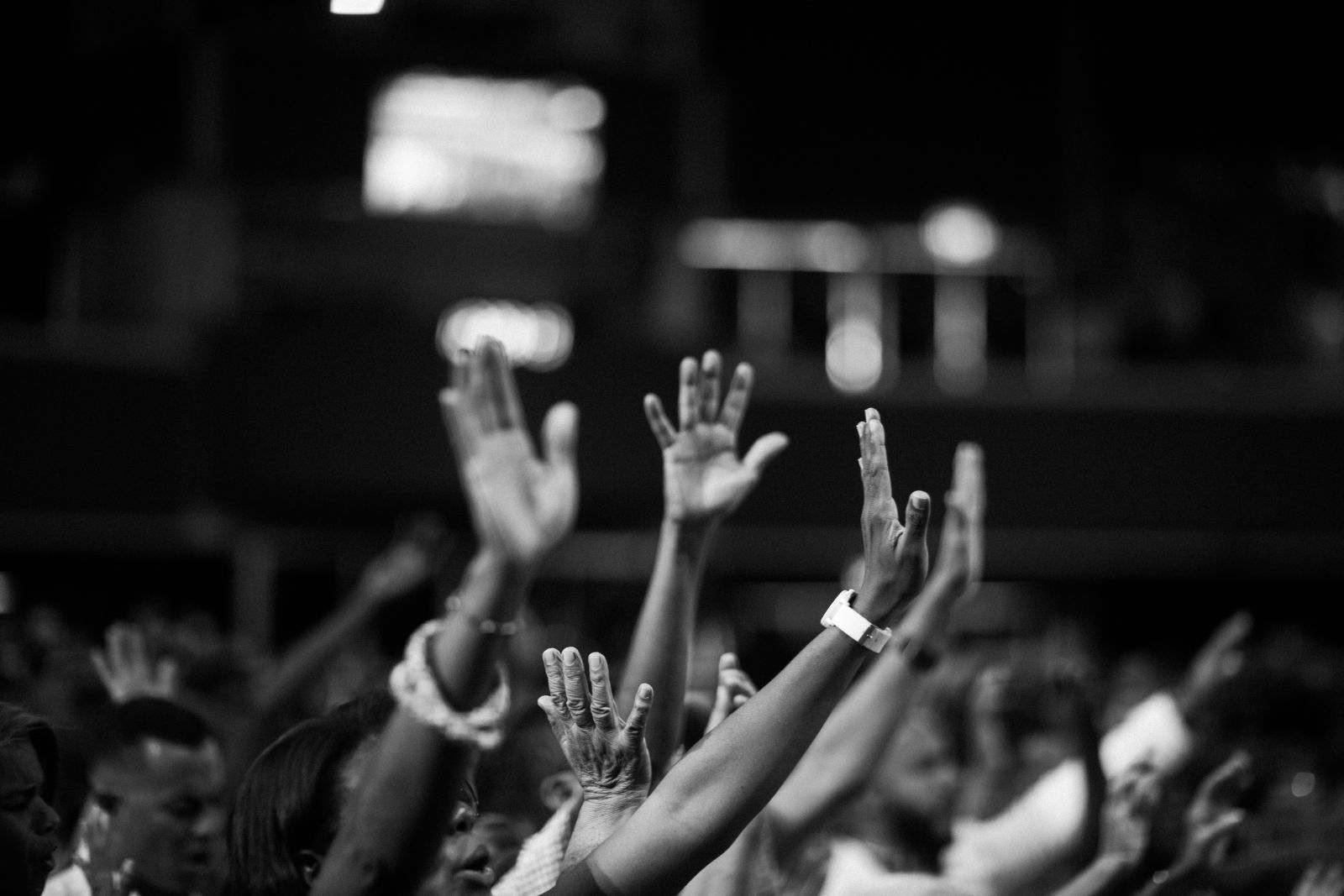 Grupo de pessoas com as mãos para cima, orando