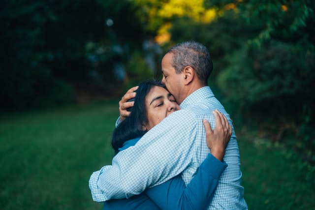 Homem e mulher negros se abraçando.