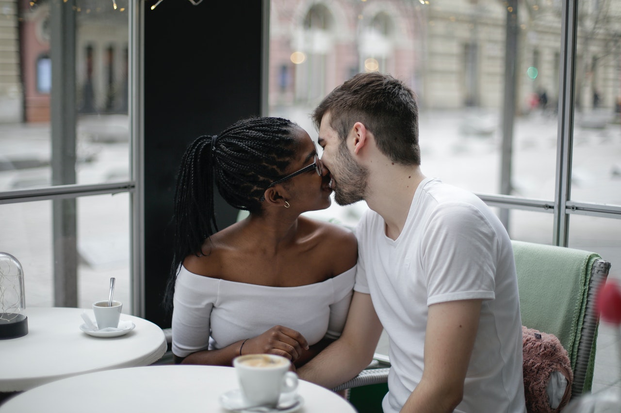Pexels/Andrea Piacquadio Homem e mulher, em um café, se beijando.