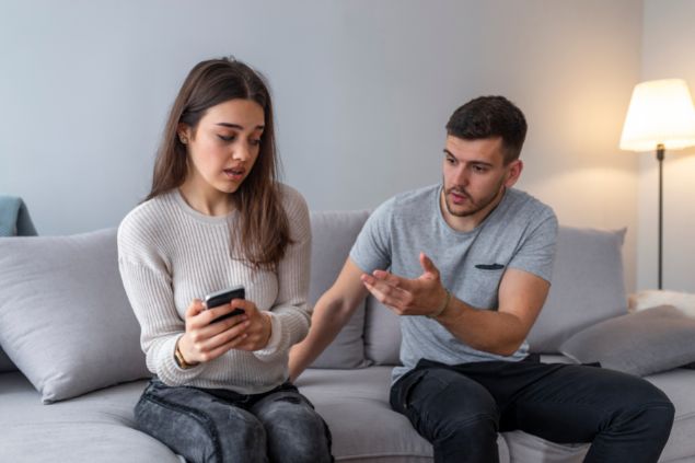 dragana991 / Getty Images / Canva Pro / Mensagens com Amor Mulher ciuemnta olhando o celular do marido, enquanto ele reclama
