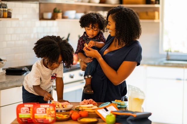 Mulher e dois meninos negros numa cozinha.