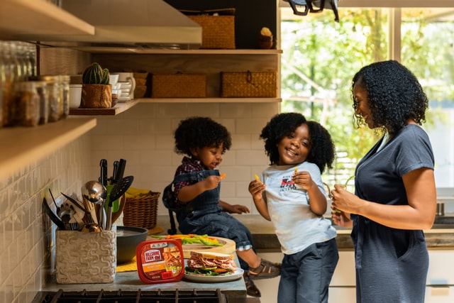 Mulher e crianças negras numa cozinha.