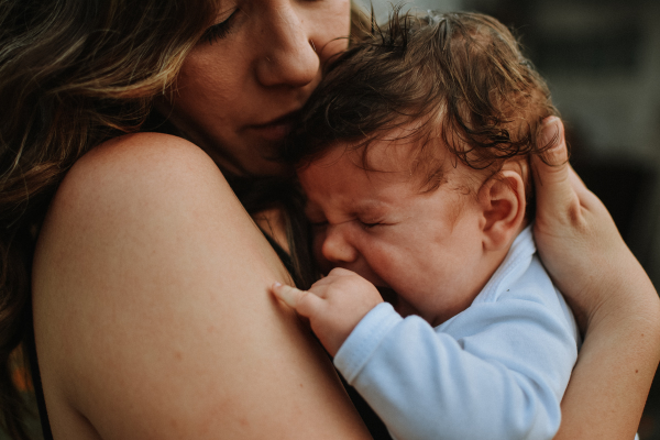 Mulher segurando bebê chorando no colo