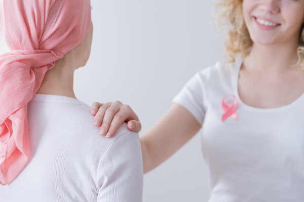 Médica com as mãos sobre o ombro de uma paciente com câncer de mama