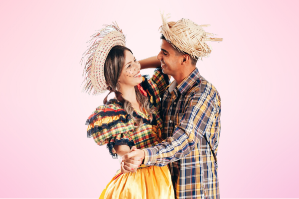 Homem e mulher com trajes de festa junina, dançando juntos.