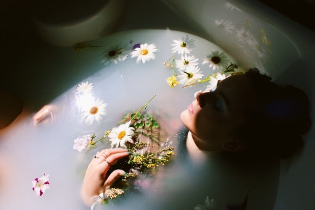 Mulher branca numa banheira com flores.