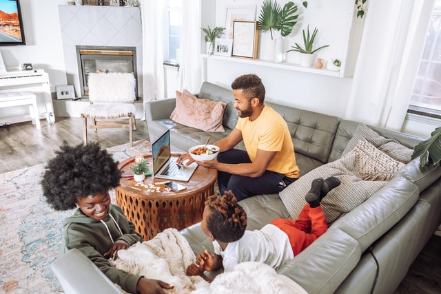 Homem e mulher negros com seus filhos numa casa clara.