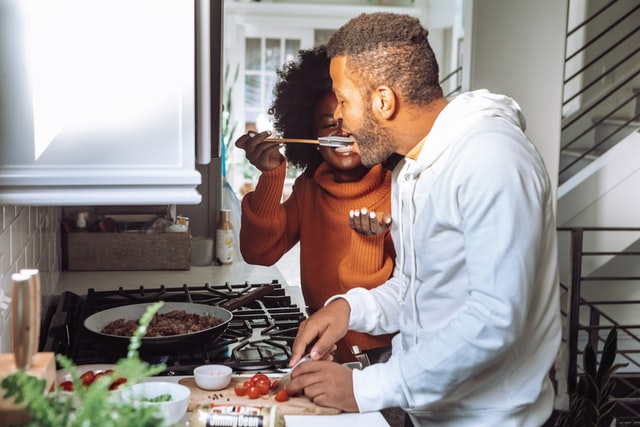 Mulher e homem negros cozinhando.