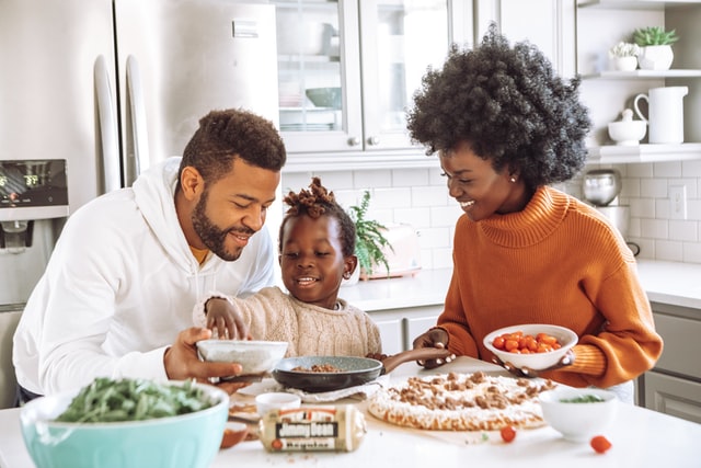 Homem, mulher e criança negros numa cozinha.
