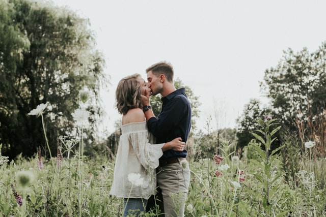 Homem e mulher se beijando em um campo.