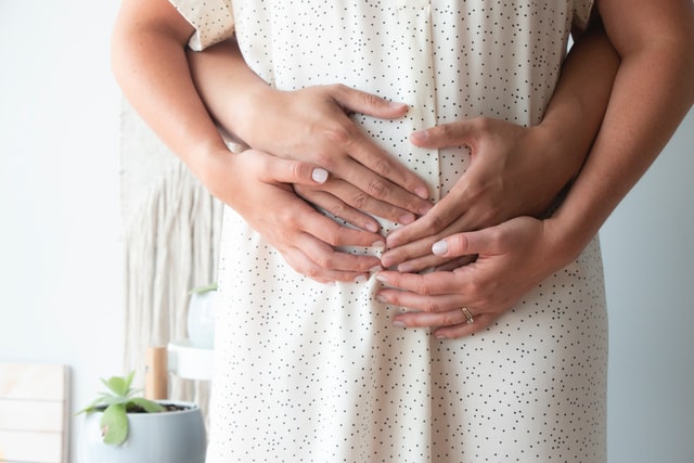 Mãos femininas e masculinas numa barriga grávida.