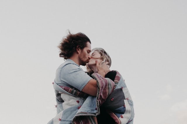 Homem e mulher brancos se beijando.