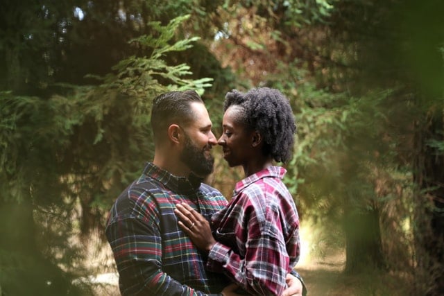 Homem e mulher abraçados na floresta.