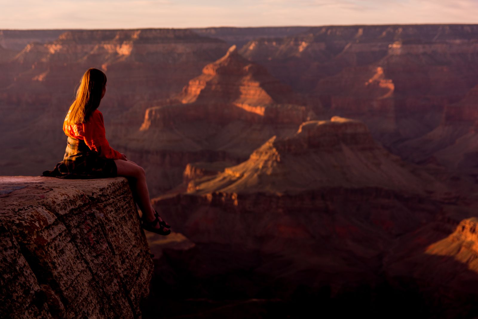 Mulher sentada em uma montanha olhando para o horizonte 