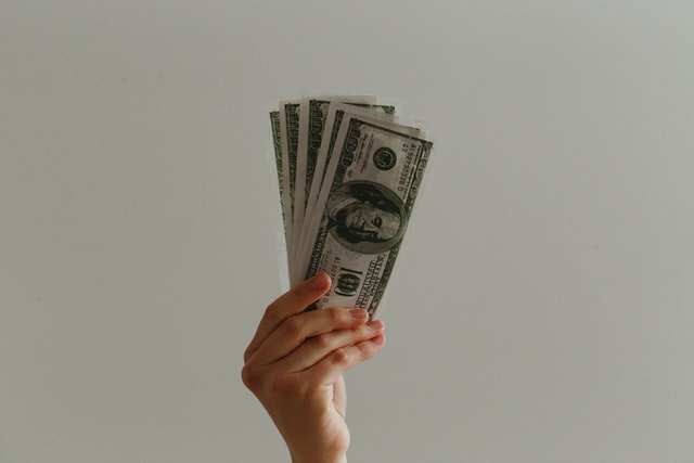 Mão branca segurando notas de dinheiro.