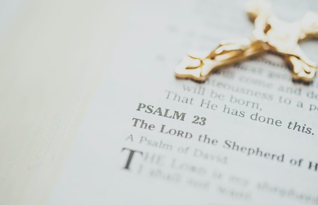 Bíblia aberta com cruz dourada em cima.