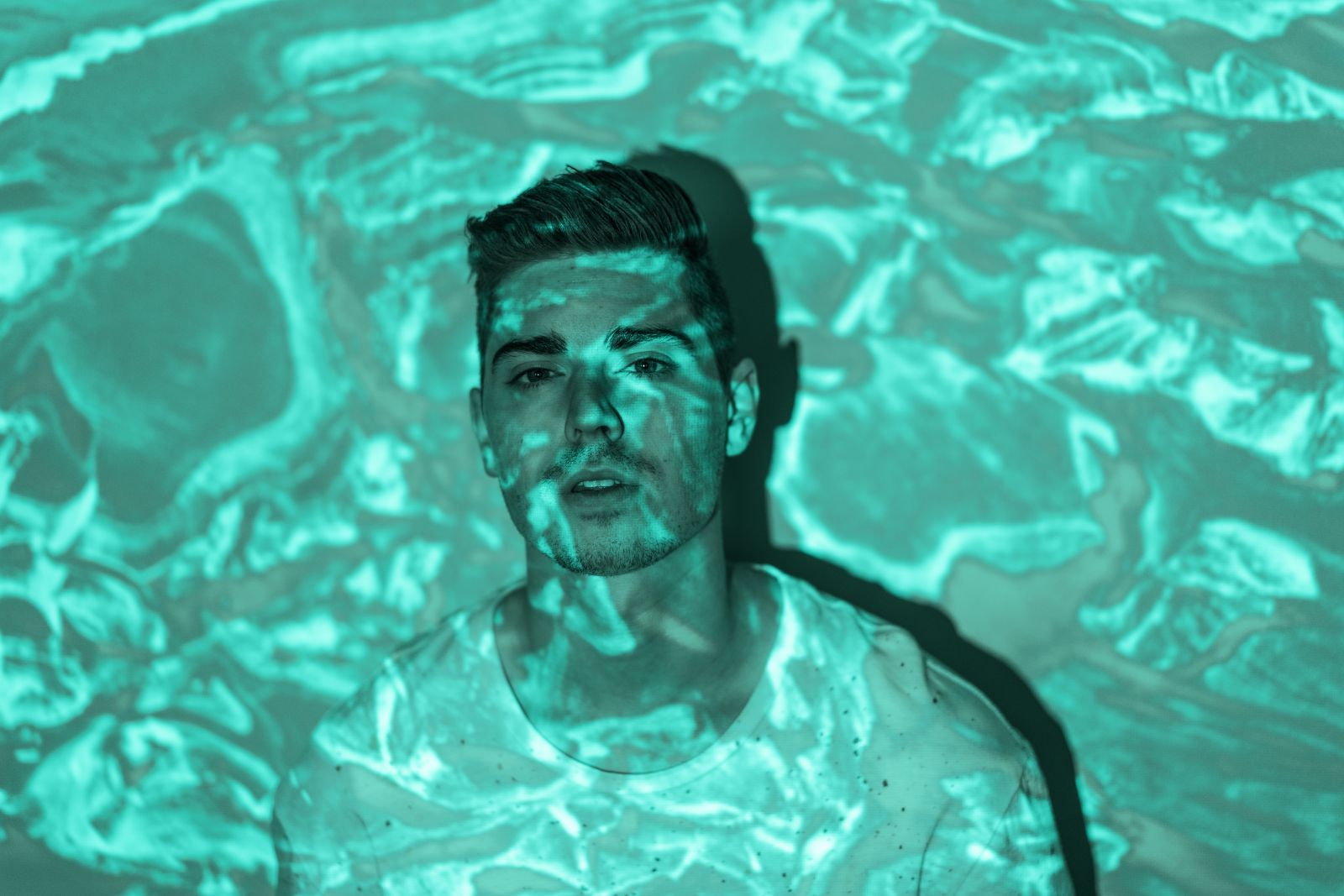 Retrato de um homem com reflexos d'água projetados sobre ele.