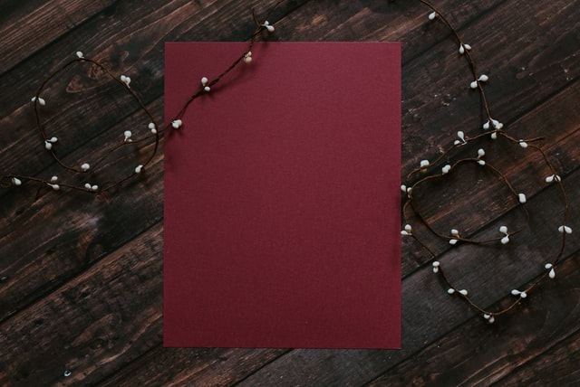 Kelly Sikkema / Unsplash Papel vermelho escuro com pisca-pisca em cima.